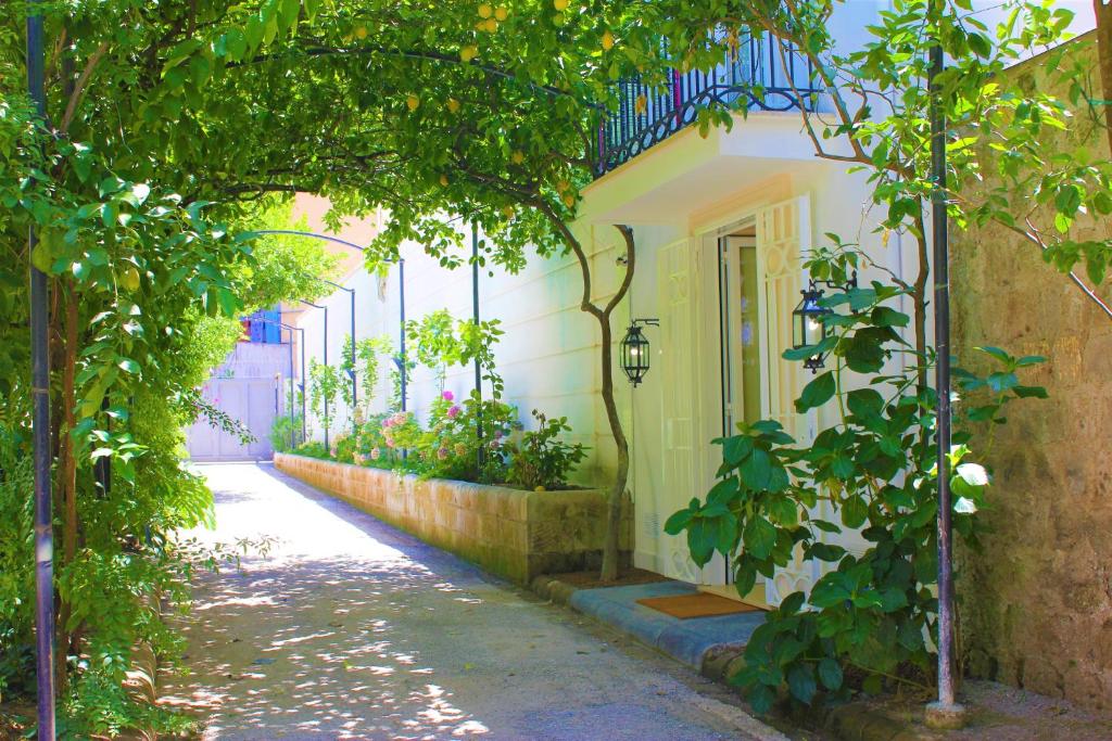 an alley with a white building with a door and plants at Dépendance La Casetta in Castellammare di Stabia