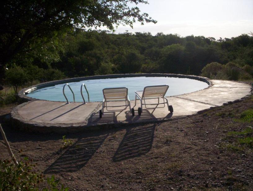 2 sillas sentadas frente a una piscina en Verde Niña Casas Serranas en Cortaderas