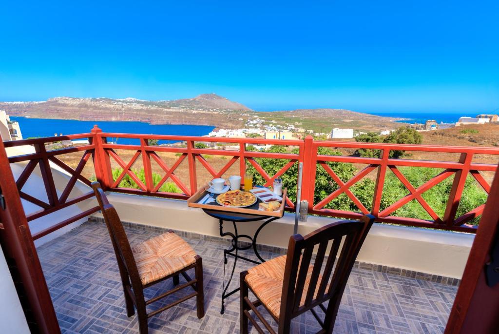 una mesa y sillas en un balcón con vistas al océano en Aspalathos Suites en Akrotiri
