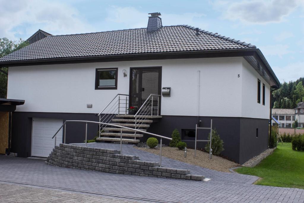 une maison blanche avec un garage et des escaliers dans l'établissement Ferienhaus am Rarbach, à Schmallenberg