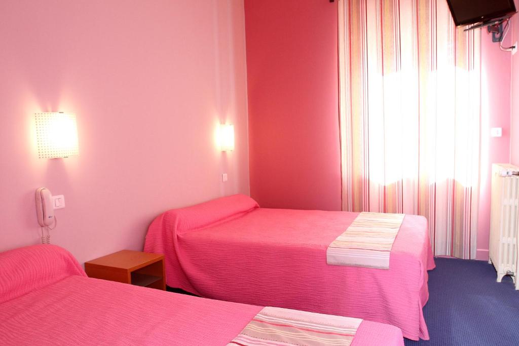 a room with two beds in a pink room at Logis Hotel Le Clos Des Oliviers in Bourg-Saint-Andéol