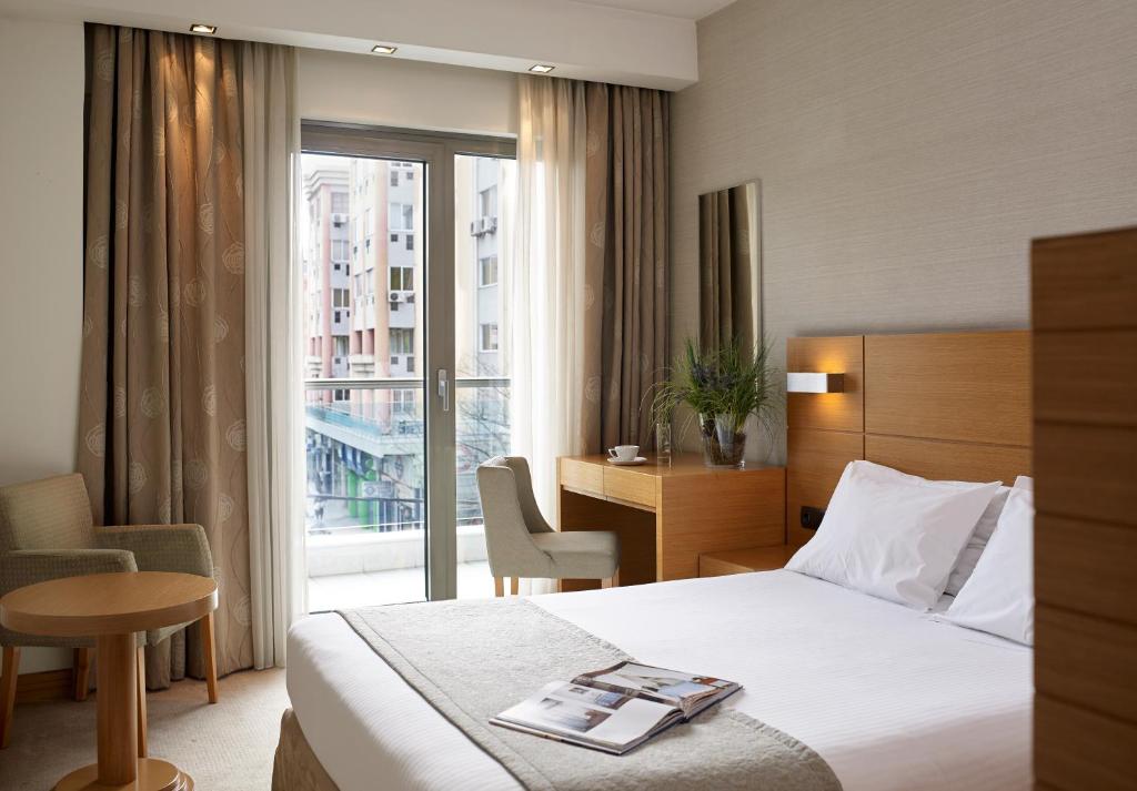 a hotel room with a bed and a desk and a window at Anatolia Hotel in Thessaloniki