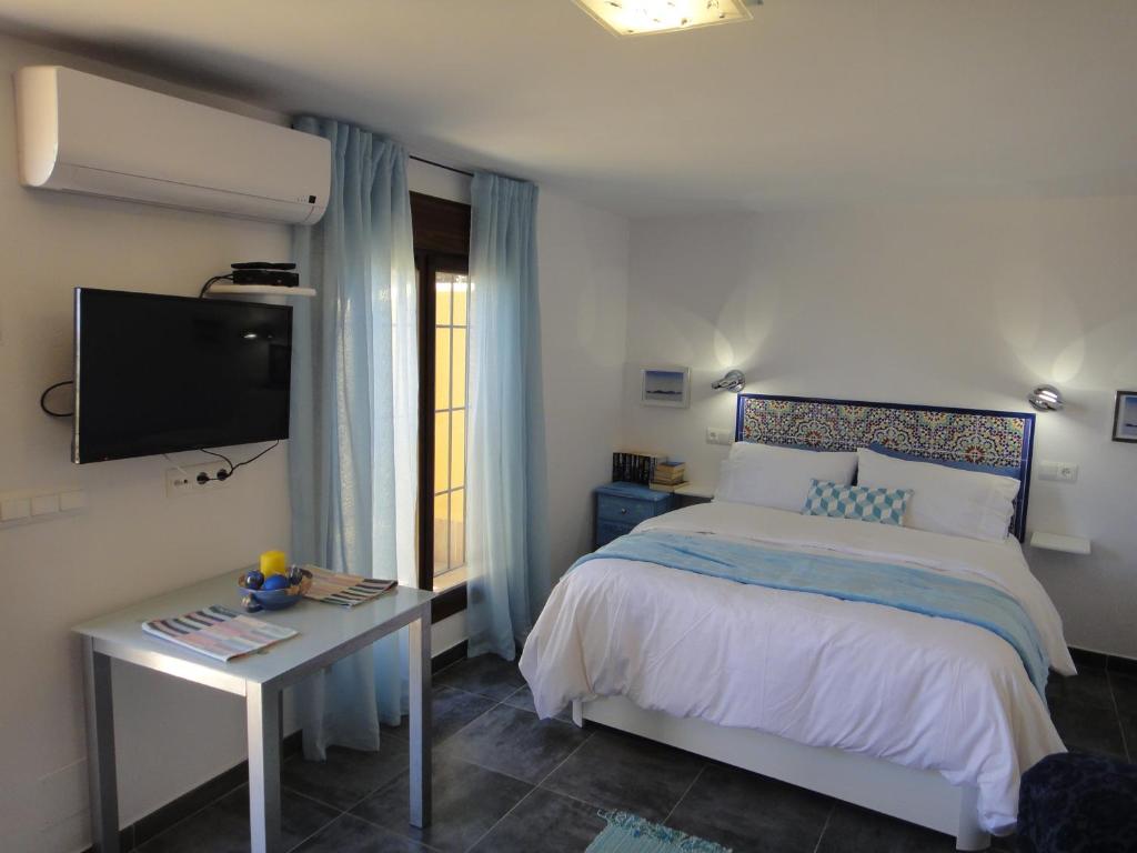 1 dormitorio con cama, mesa y TV en Casa Oasis, en Álora