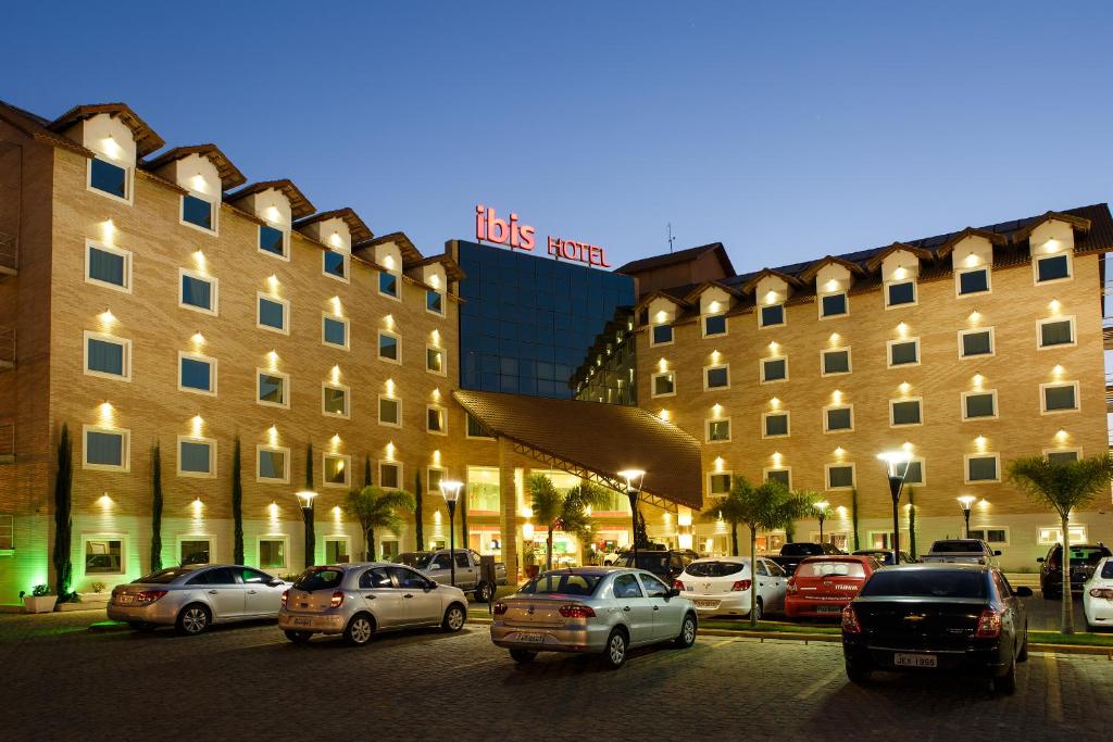 a large building with cars parked in a parking lot at ibis Vitoria da Conquista in Vitória da Conquista