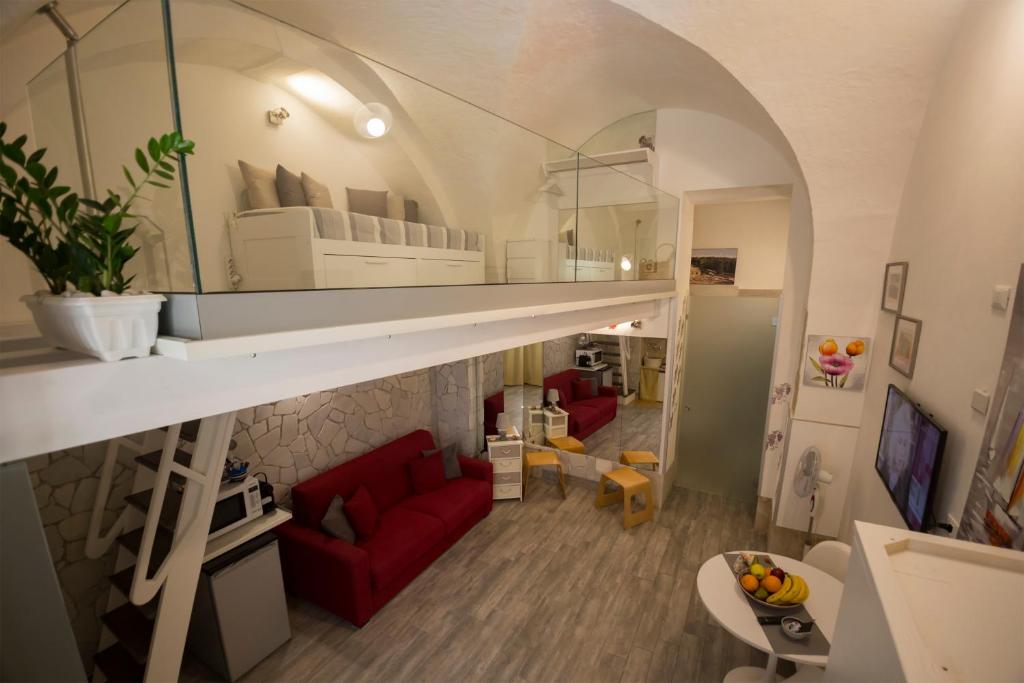 a living room with a red couch and a mirror at Dammuso di Ponente Ortigia in Siracusa