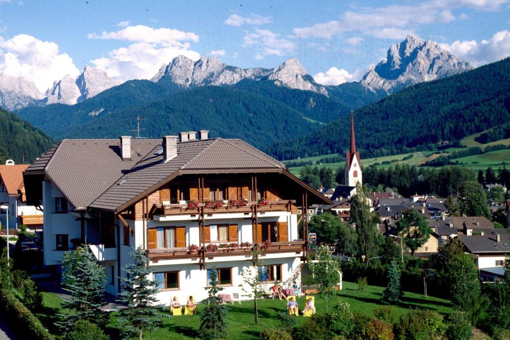 ein Haus in einem Dorf mit Bergen im Hintergrund in der Unterkunft Hotel Garní Sunnleit´n in Welsberg-Taisten
