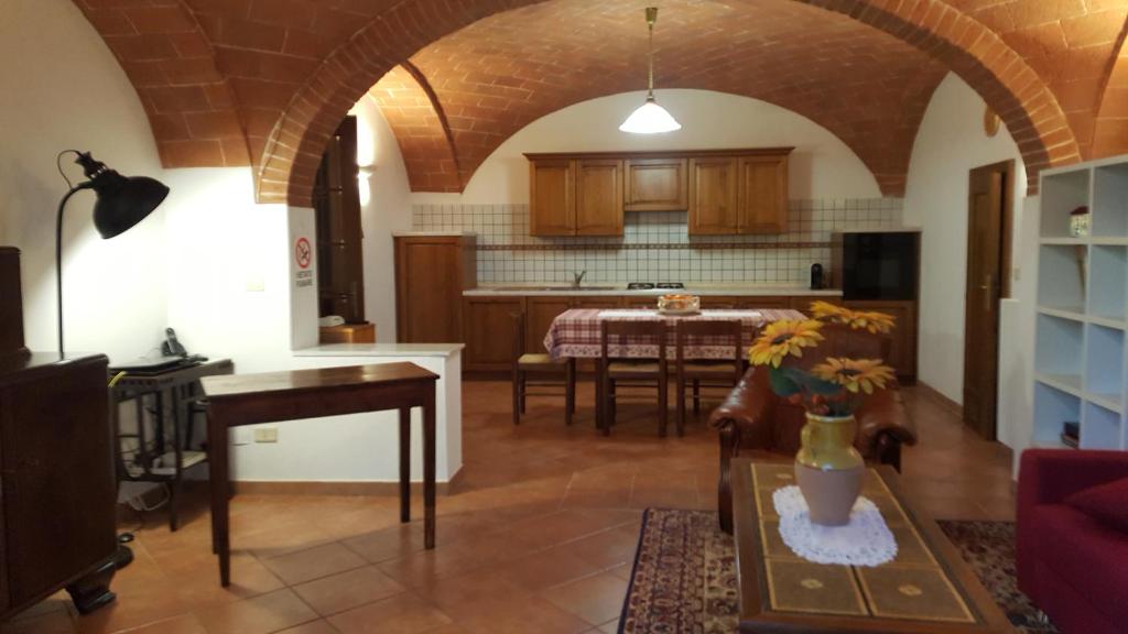 a living room with a kitchen and a table with a vase of flowers at Orto degli Ulivi in Sinalunga