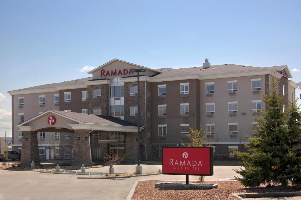 a hotel building with a sign in front of it at Ramada by Wyndham Drumheller Hotel & Suites in Drumheller