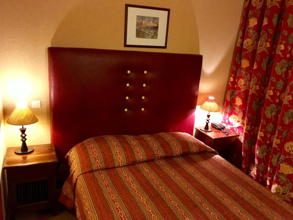 - une chambre avec un grand lit et deux lampes dans l'établissement Hotel Dorele, à Montargis