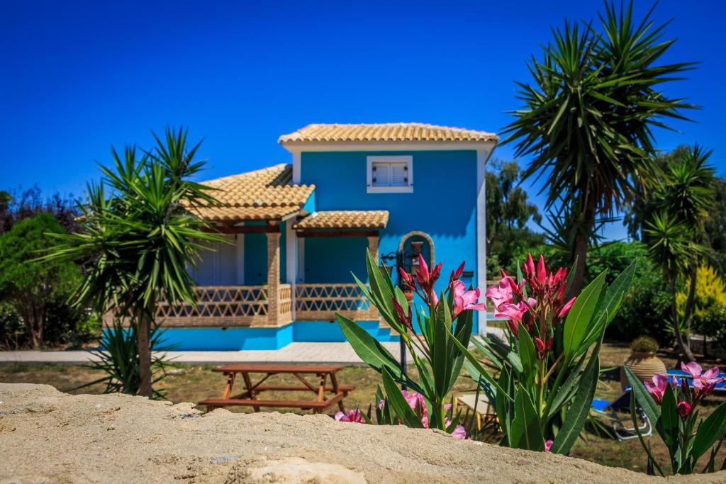 a blue house with a picnic table and some flowers at Porto Gerakas Villas in Vasilikos