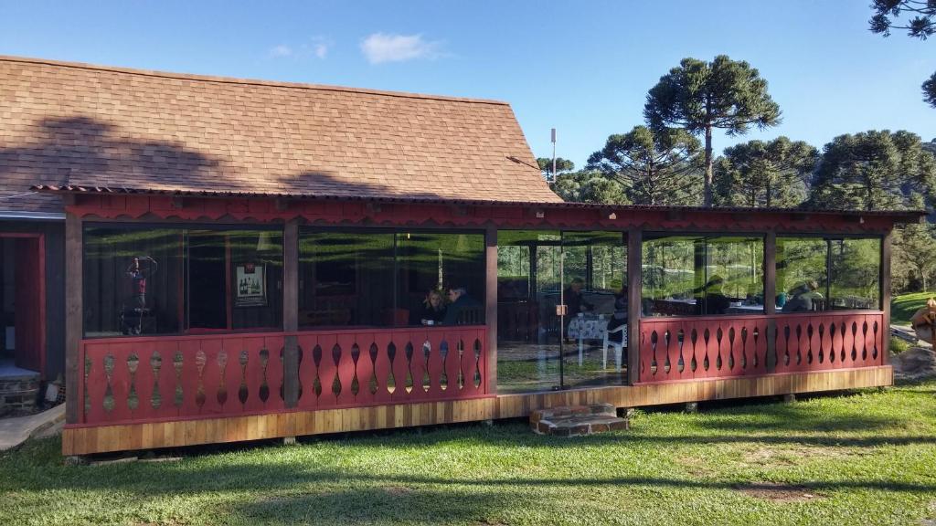 a screened in porch on a house in the grass at Pousada Cajuvá in Urubici