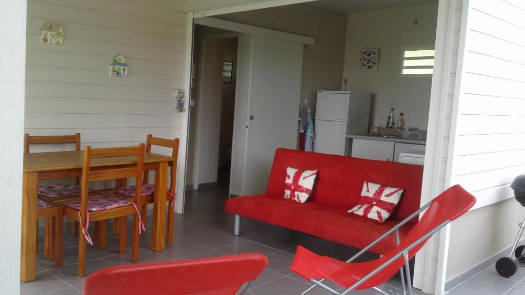 une cuisine et une salle à manger avec une chaise rouge et une table dans l'établissement Bungalow le manikou, à Le Robert