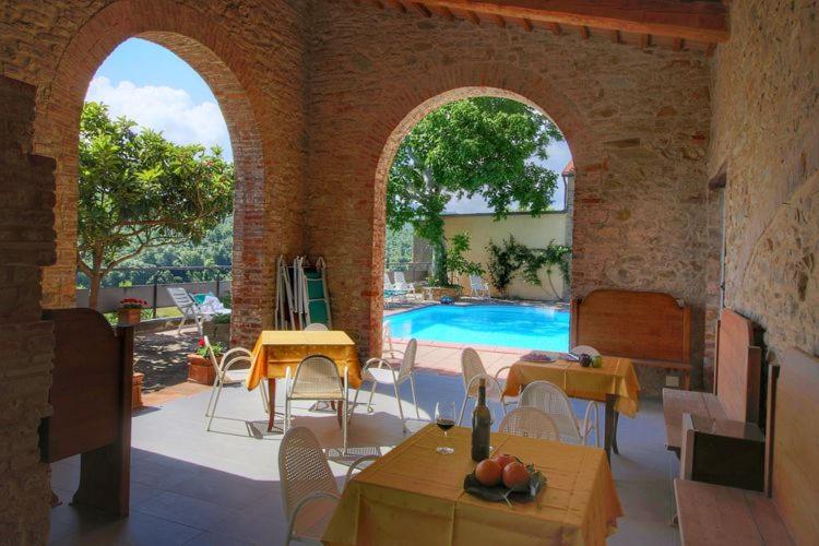 eine Terrasse mit einem Pool, Tischen und Stühlen in der Unterkunft App.to Le antiche Poste in Piegaro