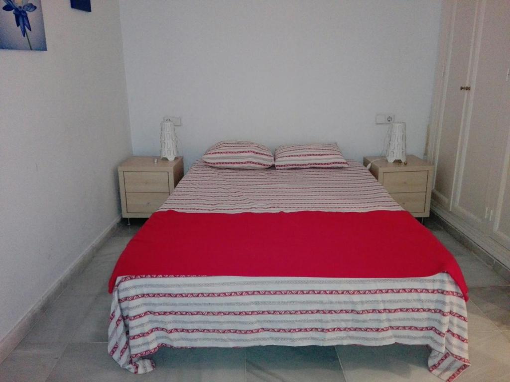 sypialnia z łóżkiem z czerwonym i białym kocem w obiekcie Céntrico Apartamento con Patio Privado w Sewilli