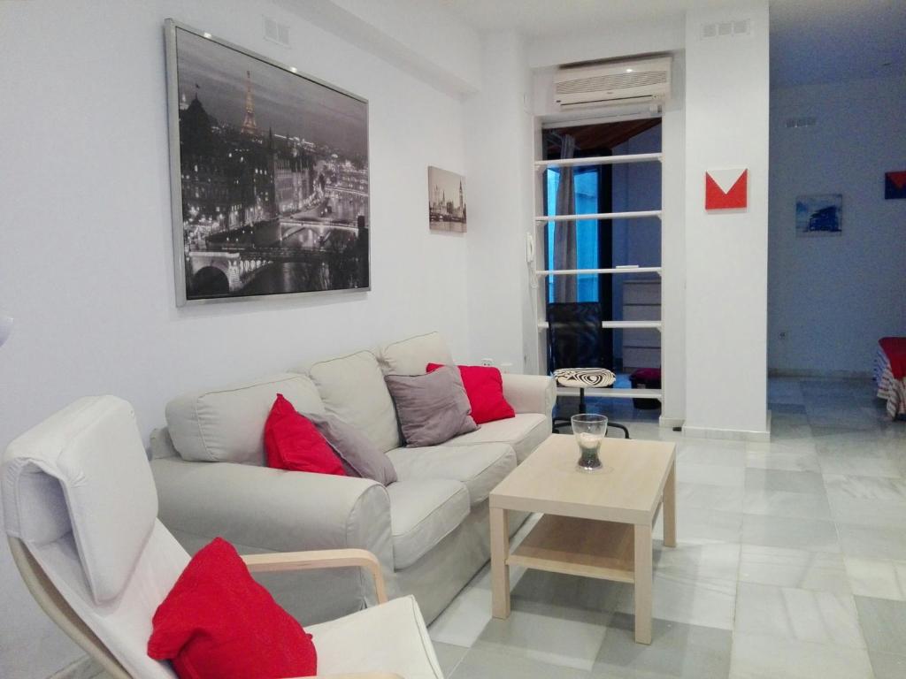 salon z białą kanapą i czerwonymi poduszkami w obiekcie Céntrico Apartamento con Patio Privado w Sewilli