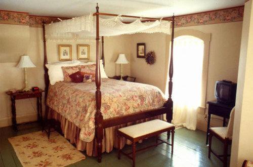 a bedroom with a canopy bed and a window at Strawberry Farm B and B in Muscatine