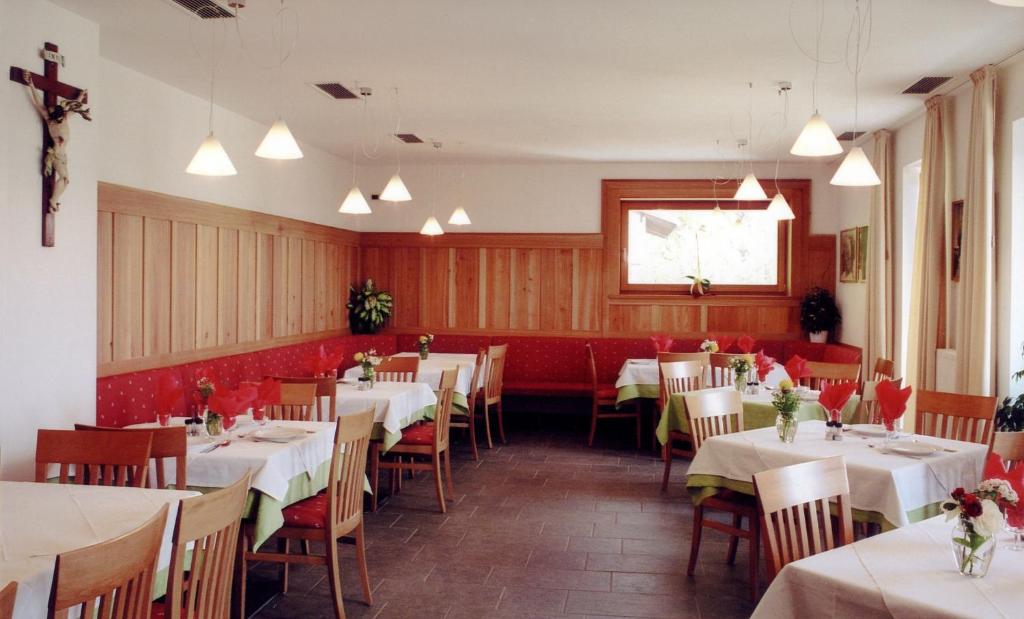 a dining room with white tables and red chairs at Al Cargà in San Vigilio Di Marebbe