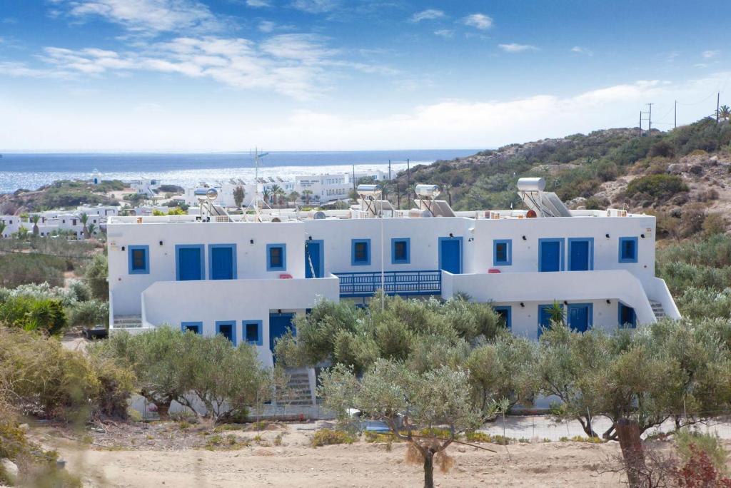 een wit huis met blauwe ramen en de oceaan bij Vardes Hotel Studios in Amoopi