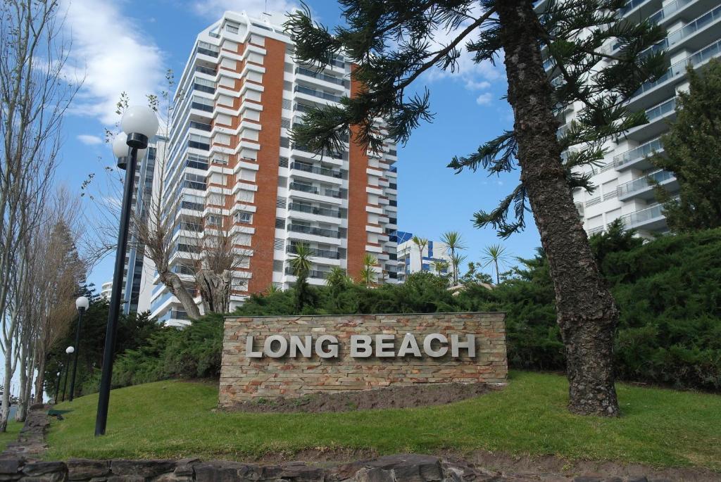 una larga señal de playa frente a un edificio alto en Torre Long Beach, en Punta del Este