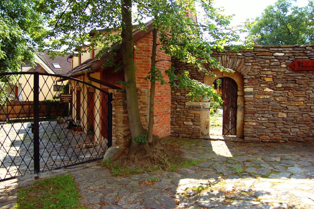 a brick building with a tree next to a fence at Penzion Kutna in Kutná Hora
