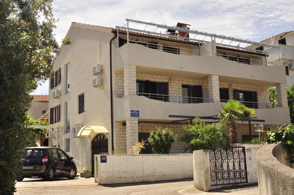 a white building with a car parked in front of it at Apartments Lucija-Klara in Brodarica