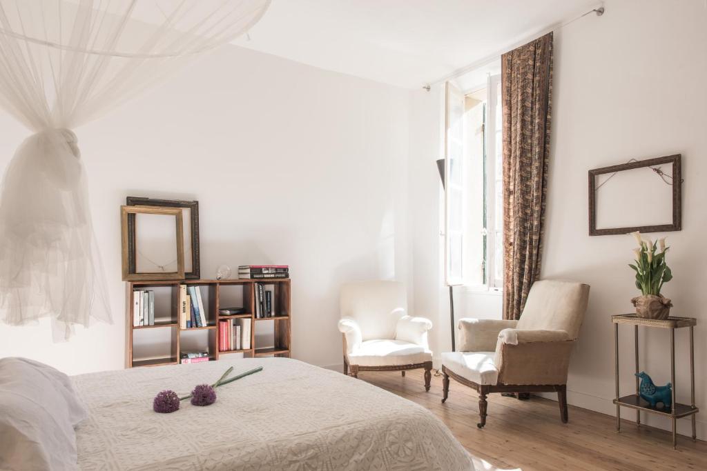 - une chambre blanche avec un lit et deux chaises dans l'établissement Appartements Avignon Centre, à Avignon