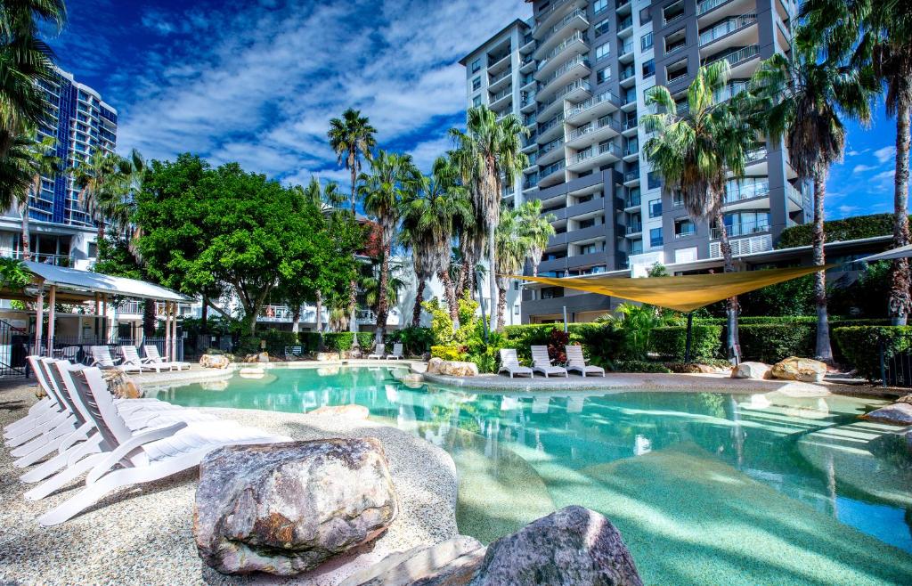 a swimming pool with chairs and a large building at Bridgewater Terraces in Brisbane