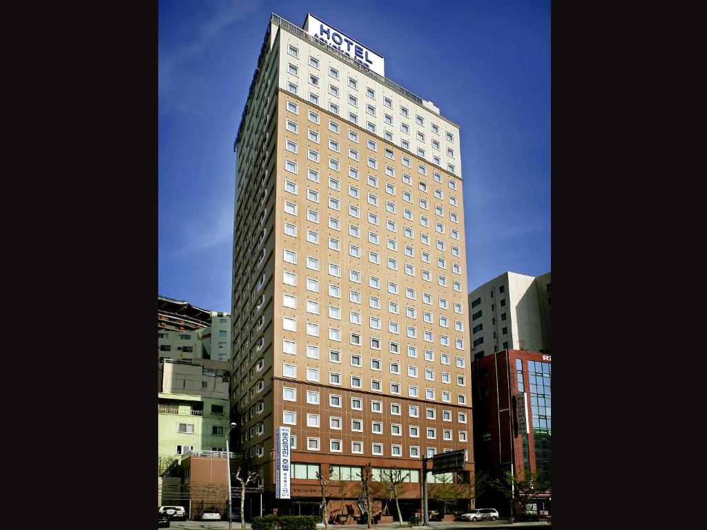 ein hohes Gebäude mit einem Schild darüber in der Unterkunft Toyoko-Inn Busan Jungang Station in Busan