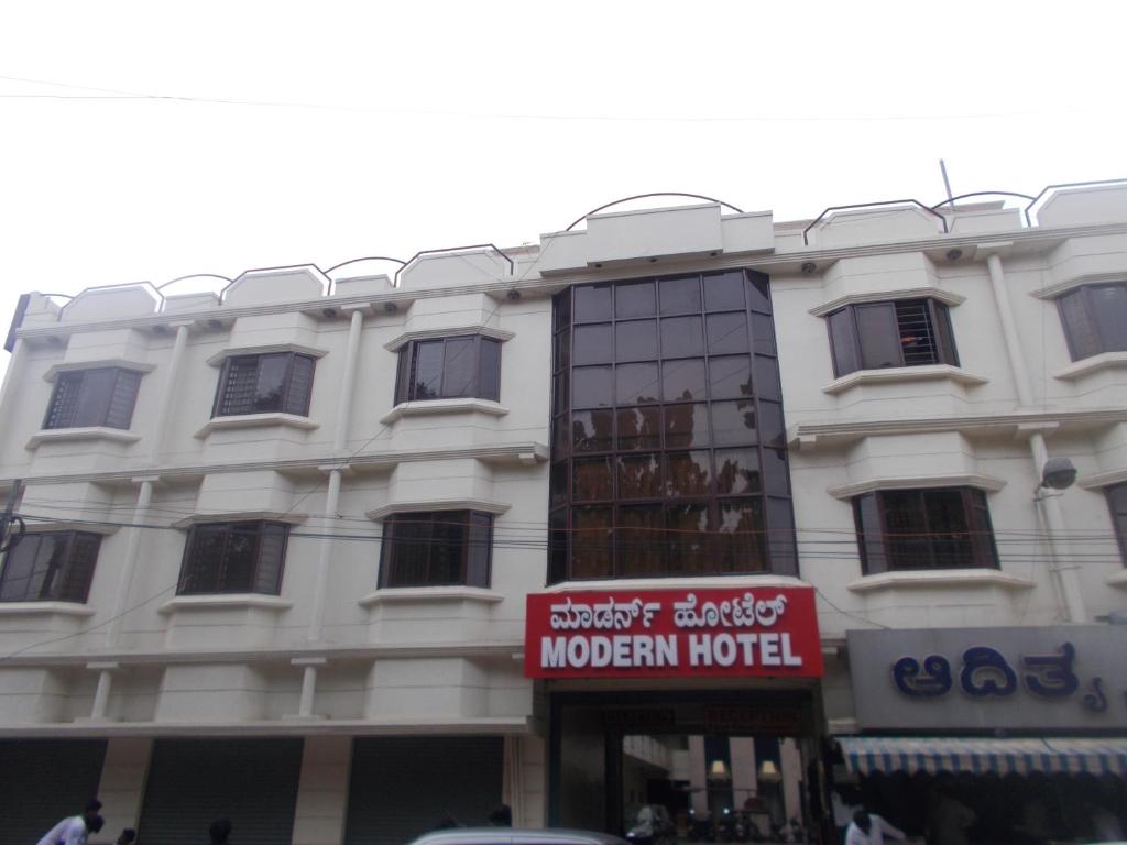 a white building with a red sign in front of it at Modern Hotel in Bangalore