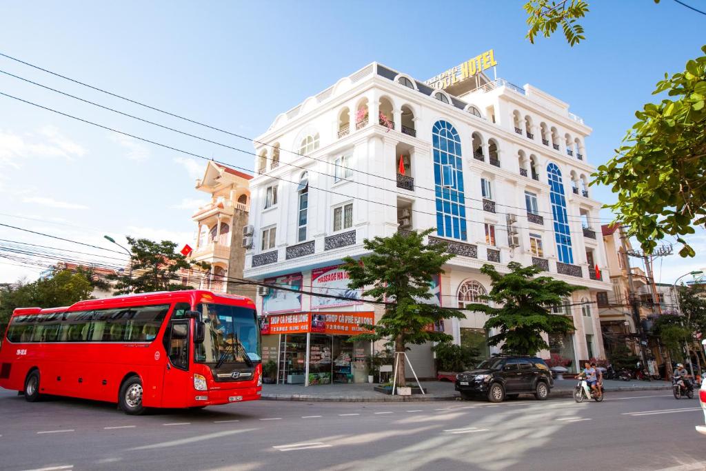 a red bus driving down a street in front of a building at HalongSeoul Hotel in Ha Long