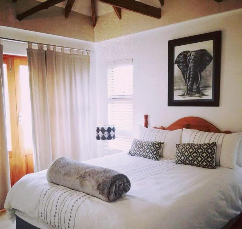 a bedroom with a large white bed with an elephant pillow on it at Milnerton Guesthouse in Cape Town