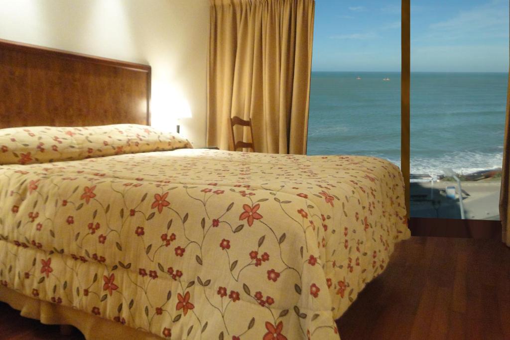 a bedroom with a bed and a view of the ocean at Hotel Amsterdam in Mar del Plata