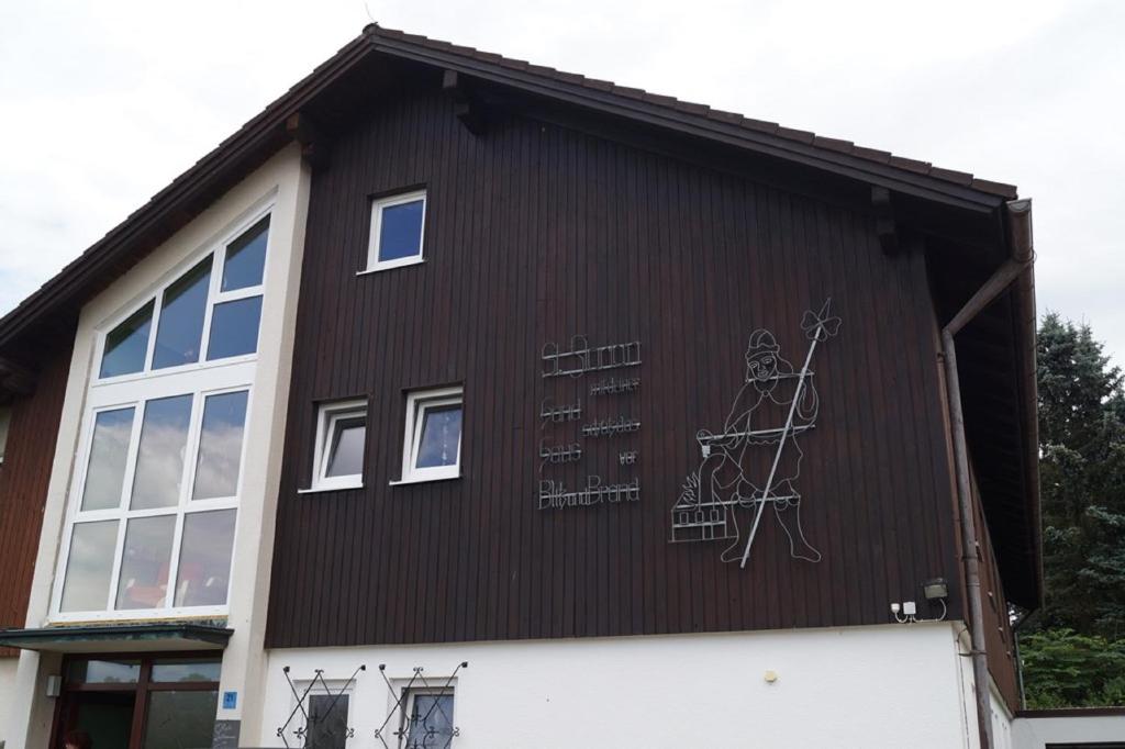 une maison avec un tableau sur son côté dans l'établissement Gästehaus am Steinwald, à Friedenfels