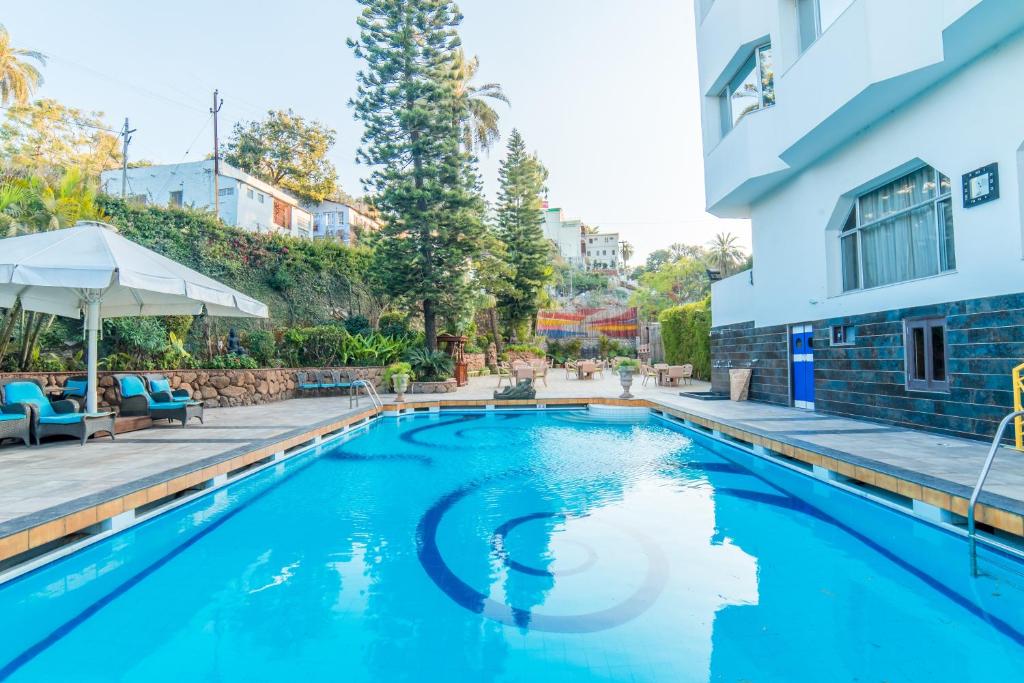 a swimming pool in front of a building at Hotel Hillock in Mount Ābu