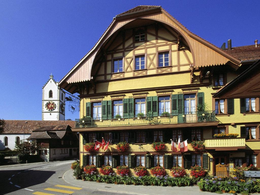 ein großes gelbes Gebäude mit einem Uhrturm in der Unterkunft Hotel Bären in Sumiswald