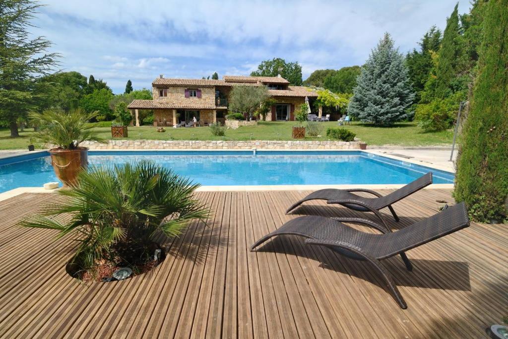 une piscine avec deux chaises et une maison dans l'établissement Mas au Cœur de La Provence & SPA, à Saint-Cannat