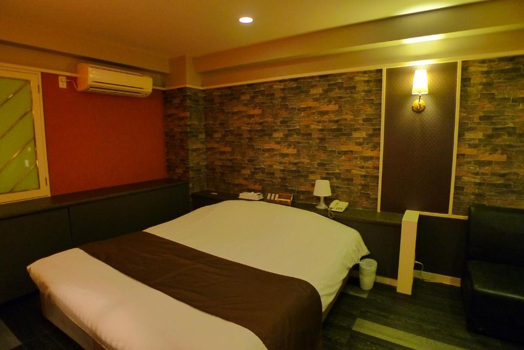 a bedroom with a bed and a brick wall at Hotel GOLF III Atsugi (Adult Only) in Atsugi