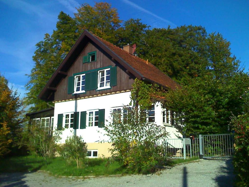 ein weißes Haus mit braunem Dach in der Unterkunft Ferienhaus beim Bienenhäuschen in Herrsching am Ammersee