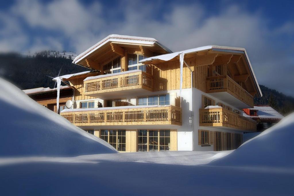 a large building with wooden balconies in the snow at Landhaus Bergglühen in Oberjoch