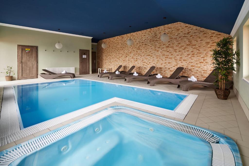 a large swimming pool with chairs and a brick wall at Amálka u Řípu in Straškov