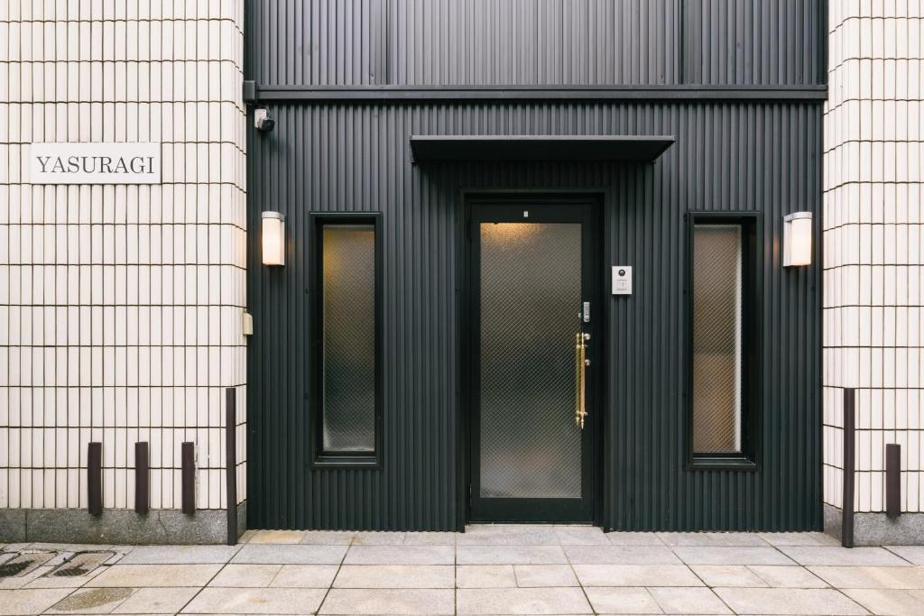 a black building with a door and two windows at Guest House Yasuragi Hakataekimae in Fukuoka