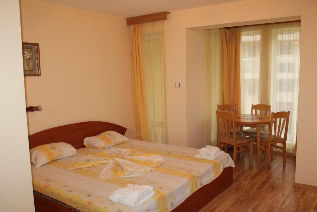 um quarto com uma cama, uma mesa e cadeiras em Apart Hotel Hetodon em Sozopol