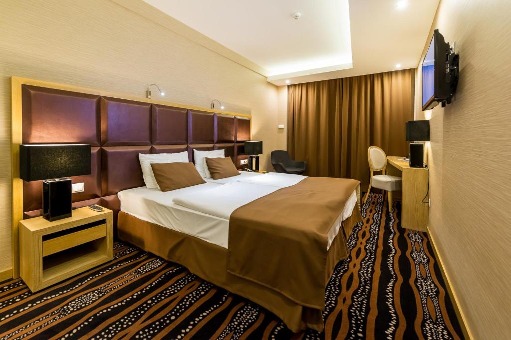 a hotel room with a bed and a flat screen tv at Aquaticum Debrecen Termal & Wellness Hotel in Debrecen