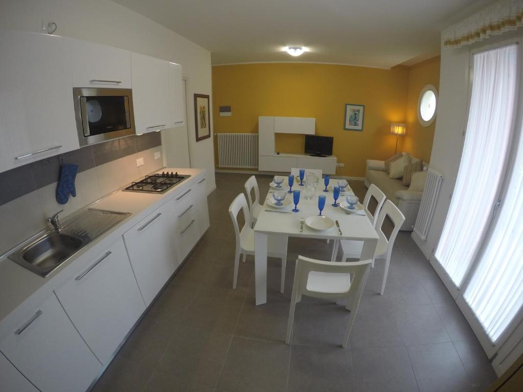 卡奧萊的住宿－Residence Orate - Agenzia Cocal，厨房以及带白色桌椅的用餐室。