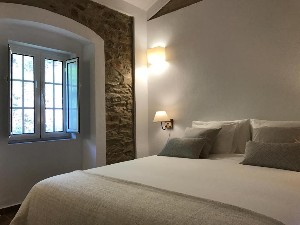 a bedroom with a large white bed with a window at Azeite de Marvão, Olivoturismo casa Mestre do Lagar in Marvão