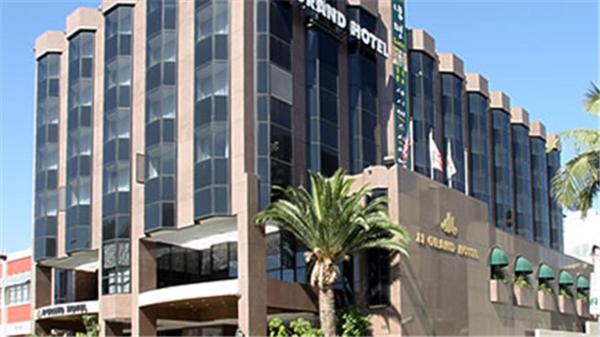 un gran edificio con una palmera frente a JJ Grand Hotel, en Los Ángeles