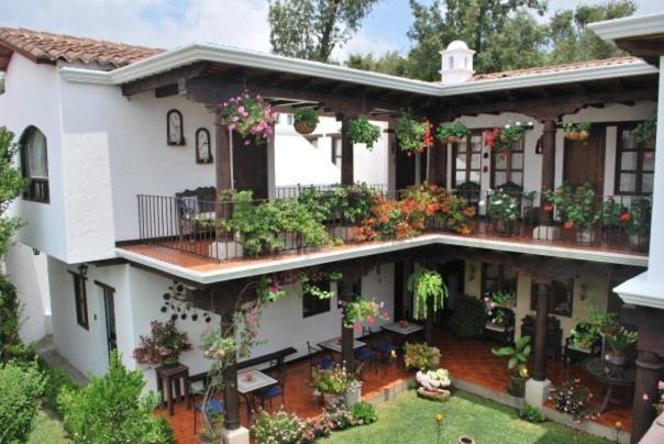 una gran casa blanca con muchas plantas en Hotel Casa Madeleine B&B & Spa, en Antigua Guatemala