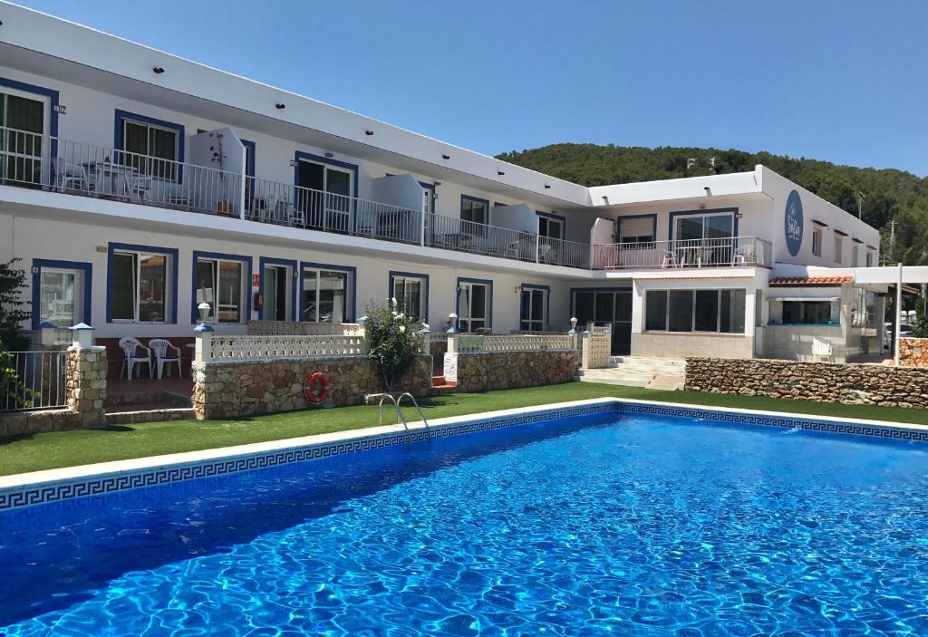 a villa with a swimming pool in front of a building at Apartamentos Cana Sofía in Cala Llonga