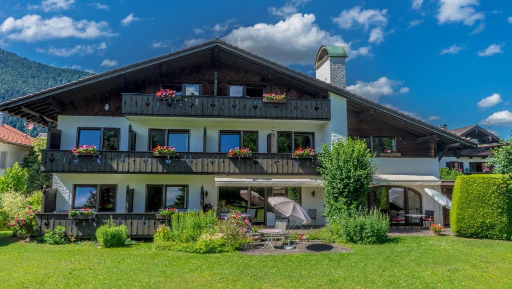 ein Haus mit einem Balkon mit Blumen darauf in der Unterkunft Hotel Garni Zugspitz in Farchant