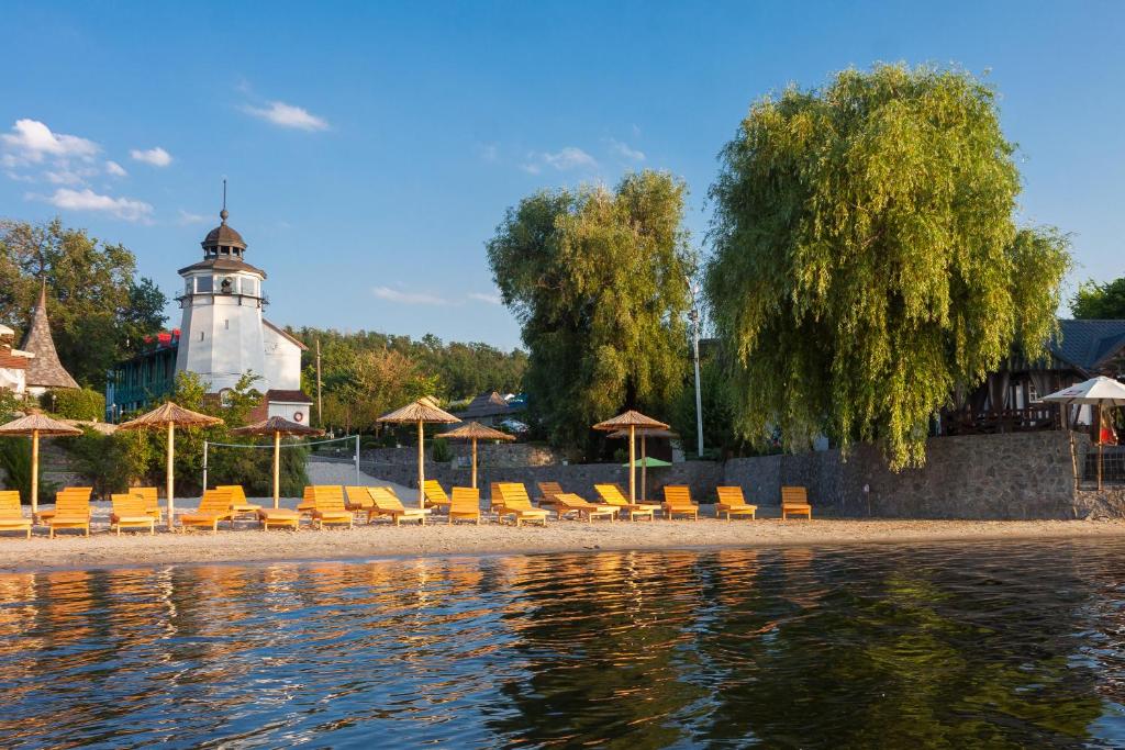 a group of chairs and umbrellas next to the water at Mayak Resort in Kam”yani Potoky